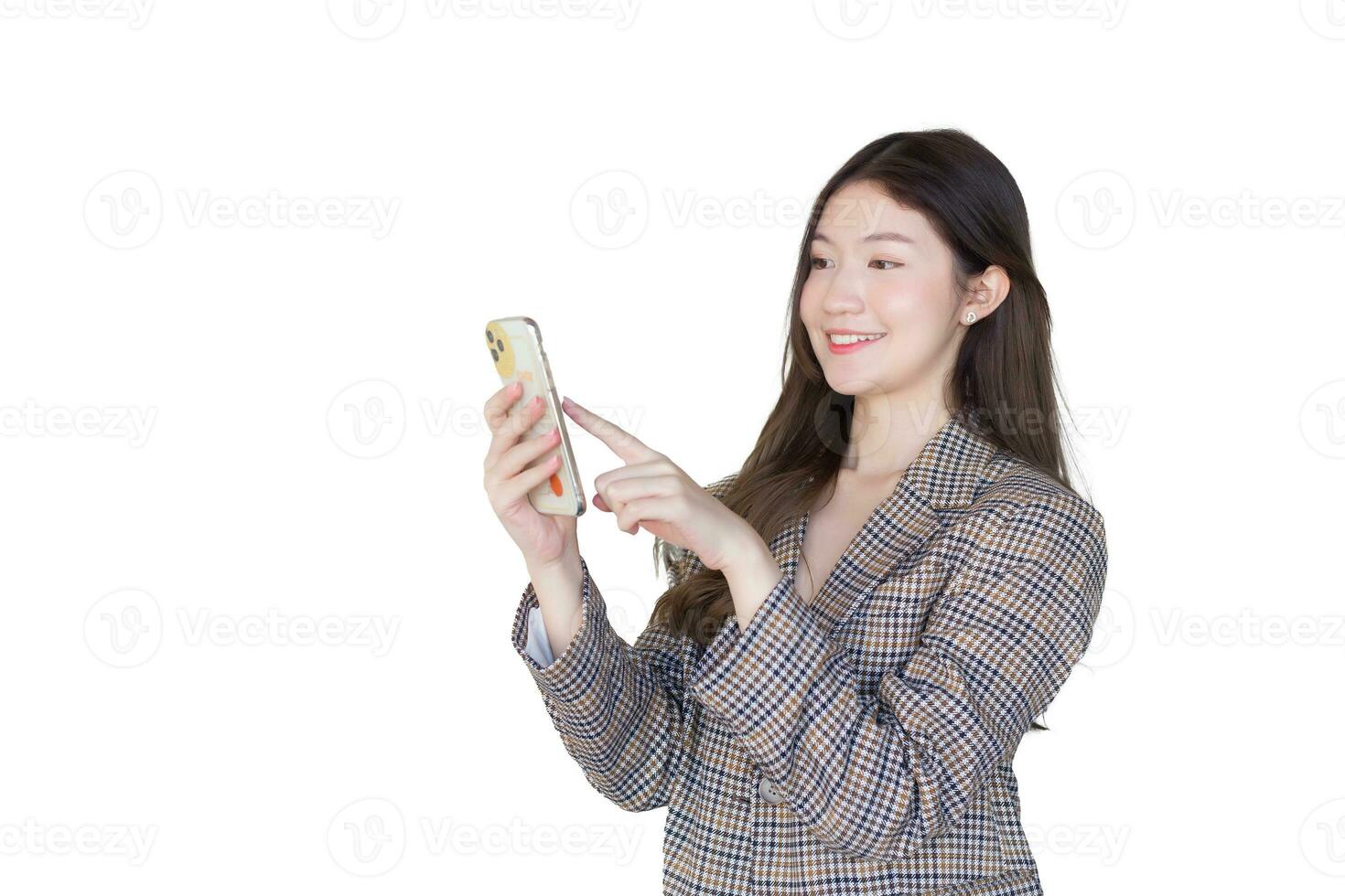 Young Asian professional woman with black long hair wearing plaid suit while she acts enjoy with success of work using smartphone while isolated on white background. photo