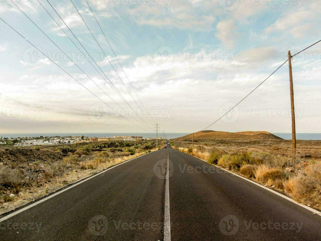 an empty road with power lines and a blue sky photo