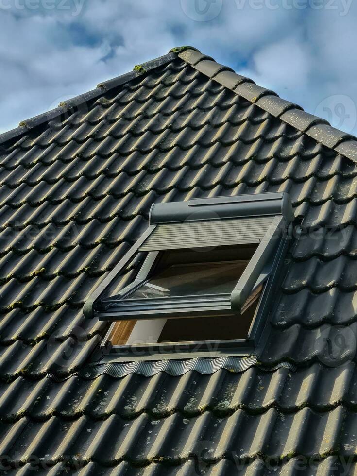 Open roof window in velux style with black roof tiles. photo