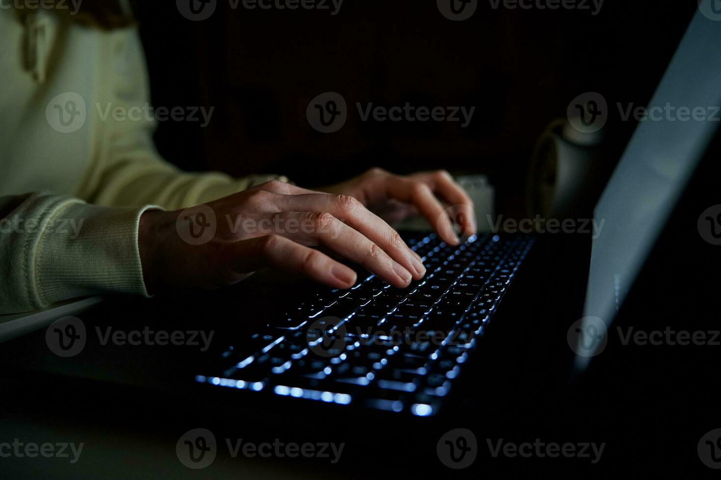 Anonymous woman working on laptop at night photo