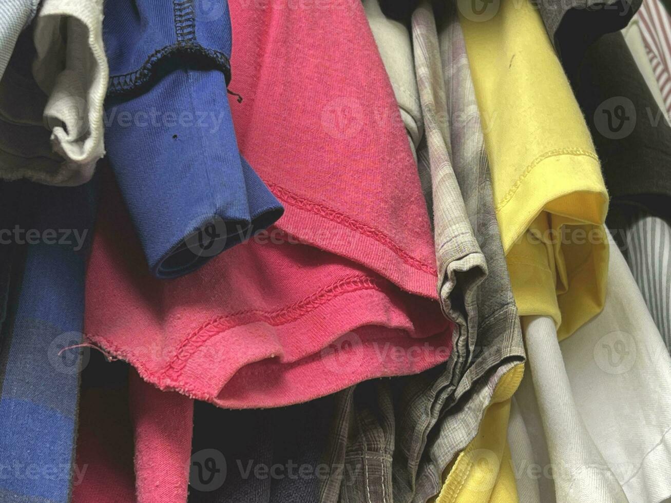 stack of different colorful clothes in a closet photo