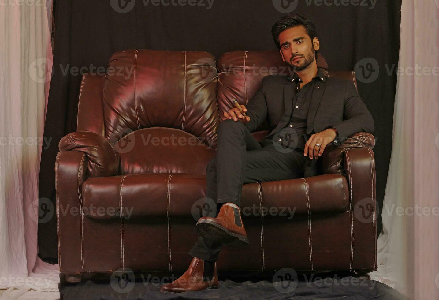 a man sitting on a brown leather couch photo