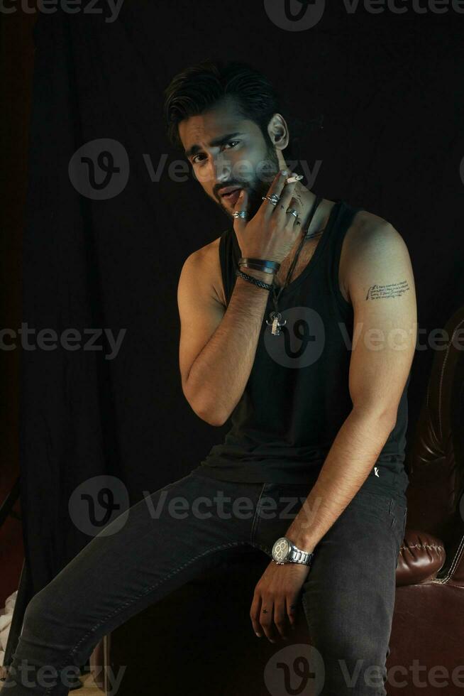 a man sitting on a leather chair with a cigarette photo