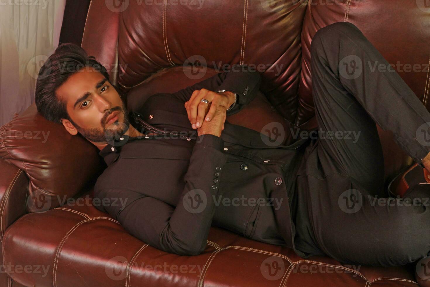 a man sitting on a brown leather couch photo