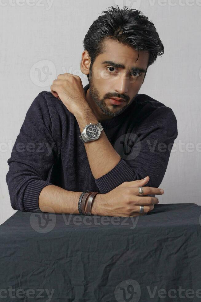 a man with a beard and a watch is sitting at a table photo