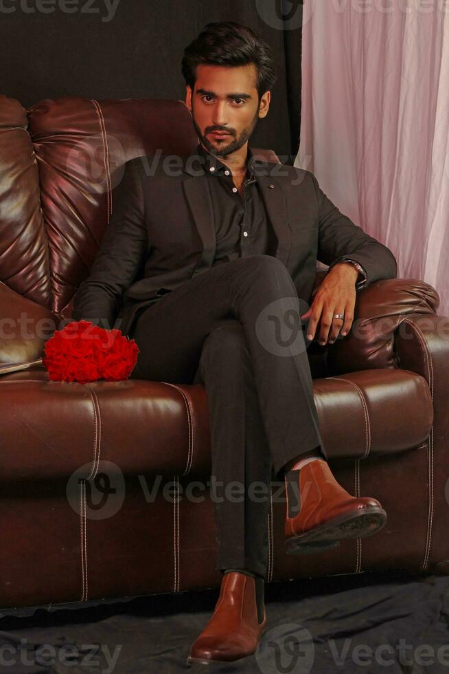 a man sitting on a brown leather couch photo