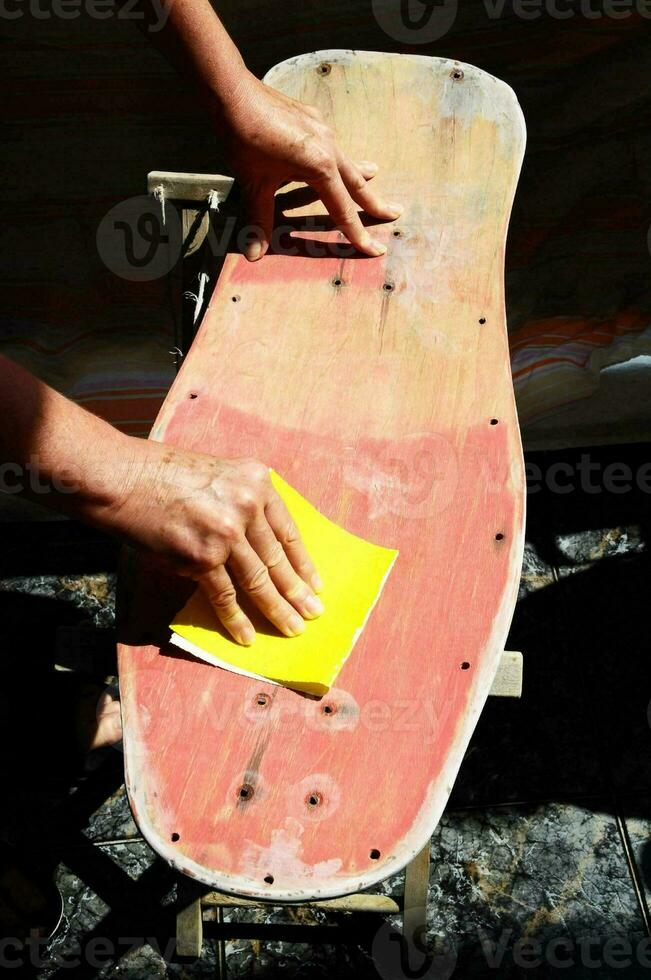 a person is sanding a skateboard with a yellow sponge photo
