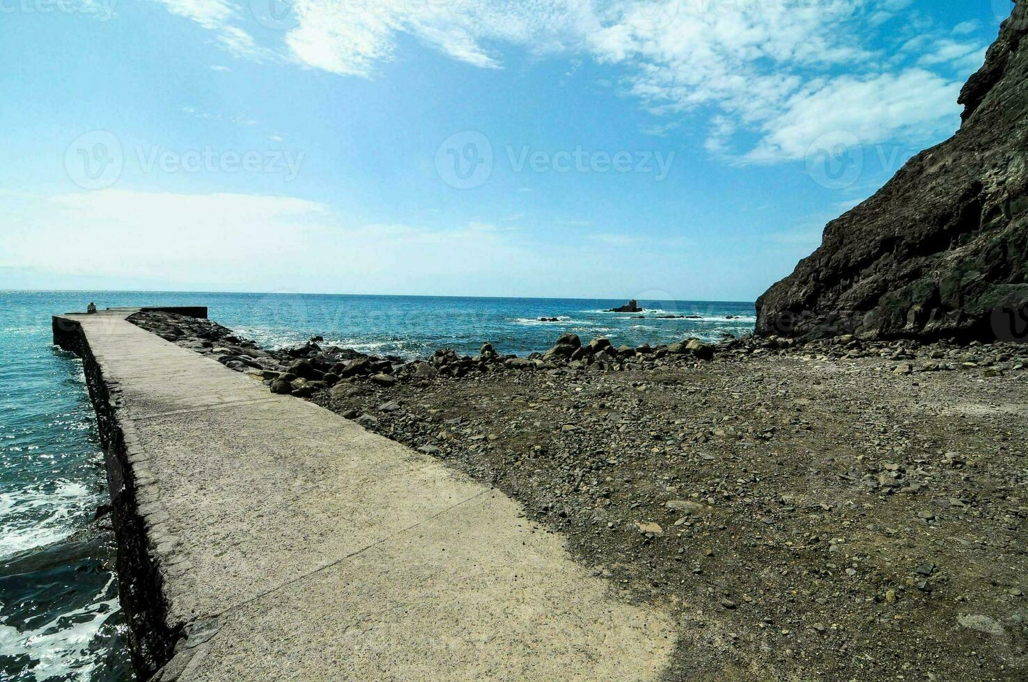 a walkway along the coast with rocks and water photo