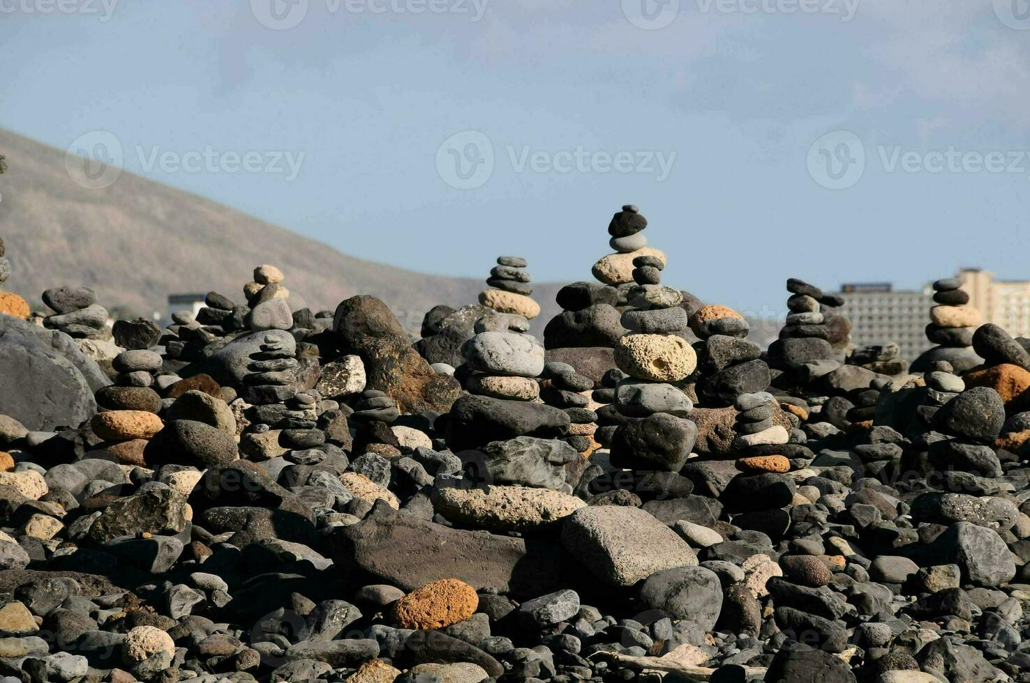 a pile of rocks on the beach with a city in the background photo