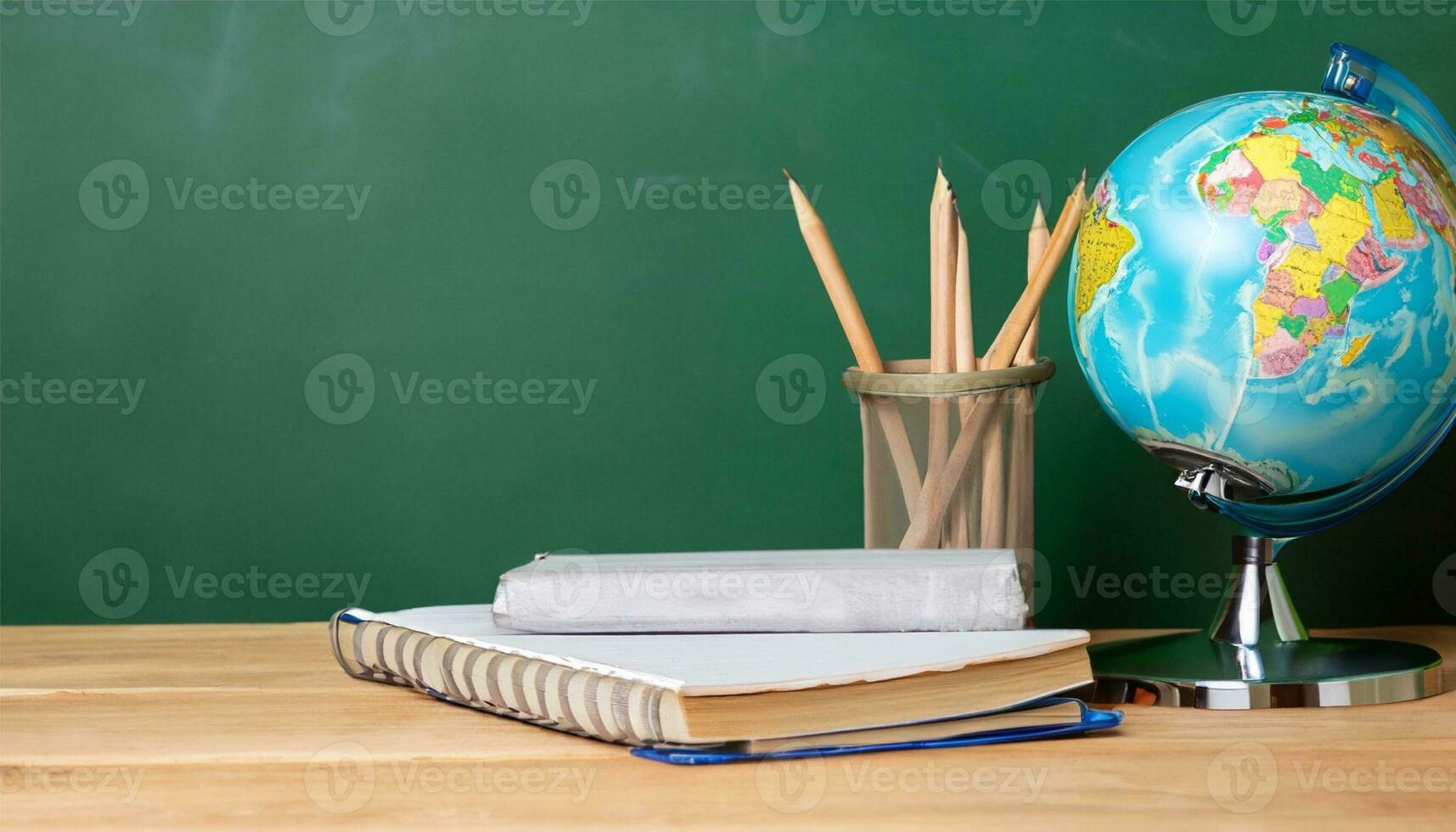 globe, pencil, pen and book on a green blackboard background and empty space on left side photo