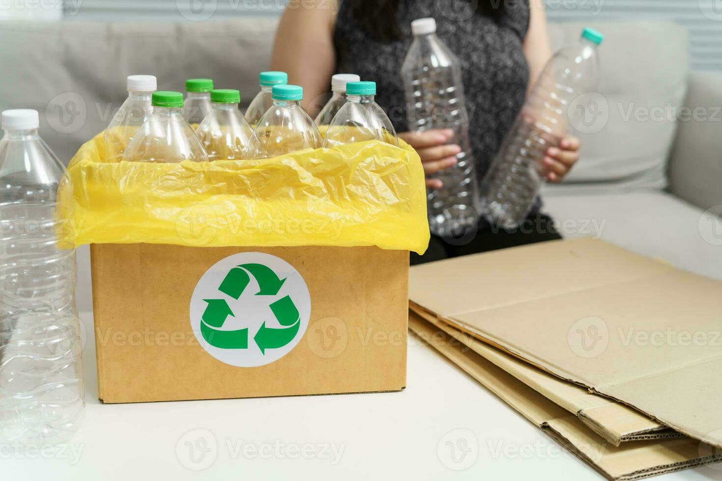 Home recycle eco green zero concept Woman throwing empty plastic bottle in recycling bin with yellow garbage bags at home. photo