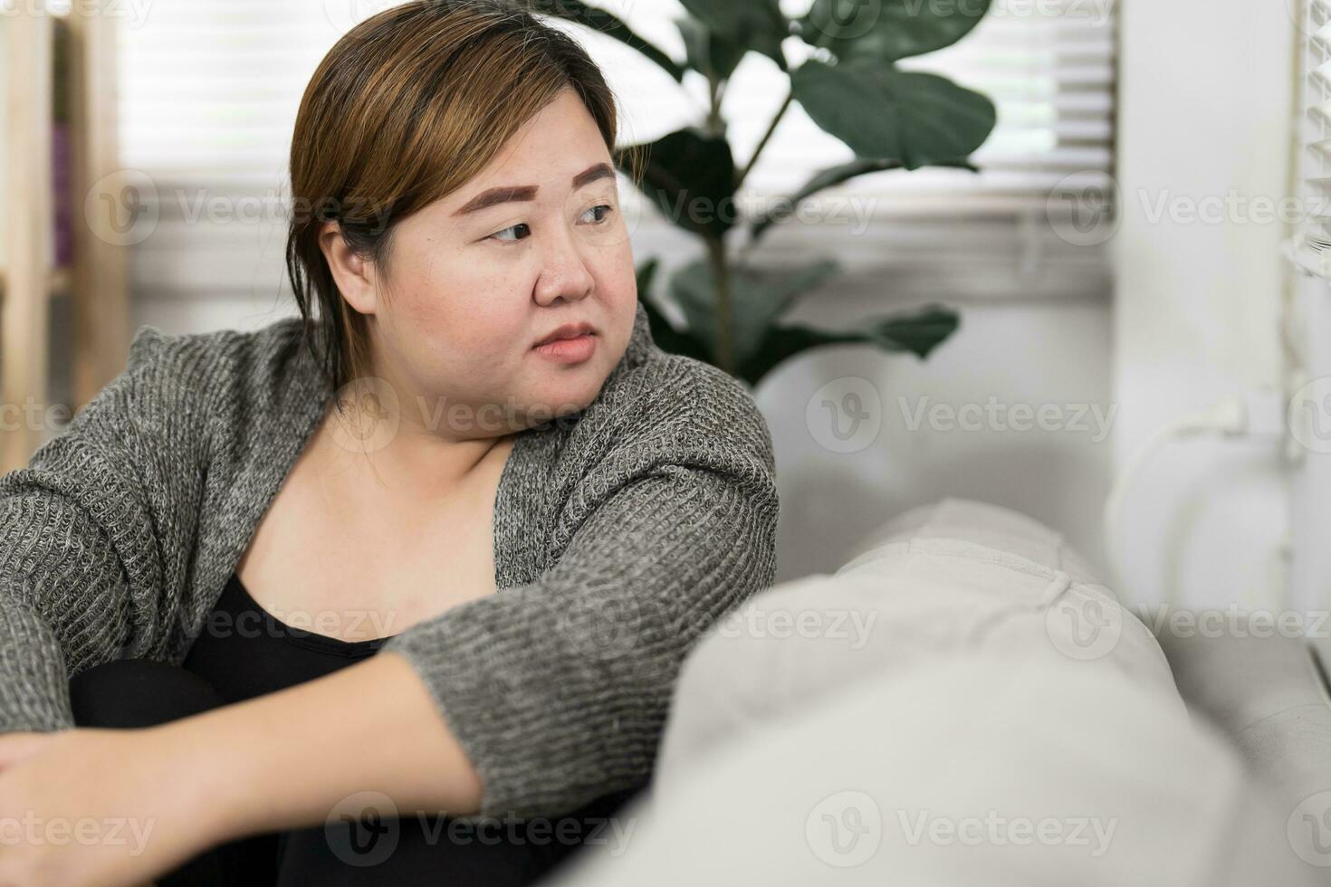 Sad Overweight plus size woman thinking about problems on sofa u photo