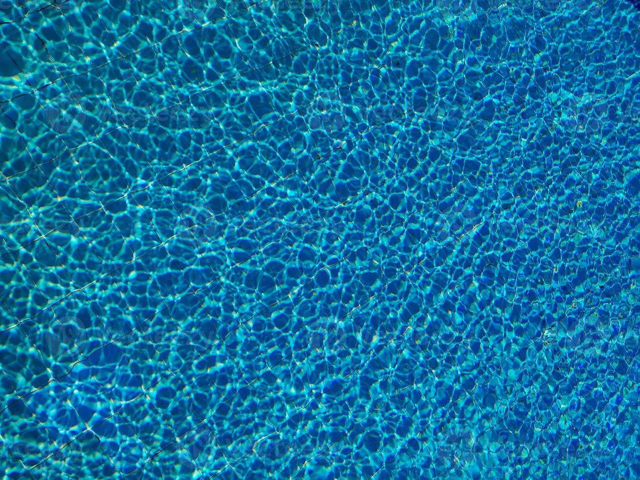 Blue water ripple in swimming pool with sun reflections photo