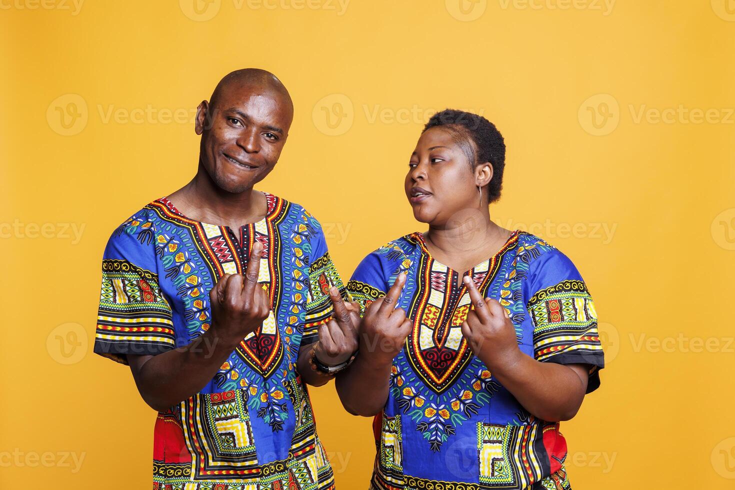 Rude african american couple showing middle finger gesture and looking at camera with angry expression. Furious man and woman demonstrating offensive and bad behavior studio portrait photo