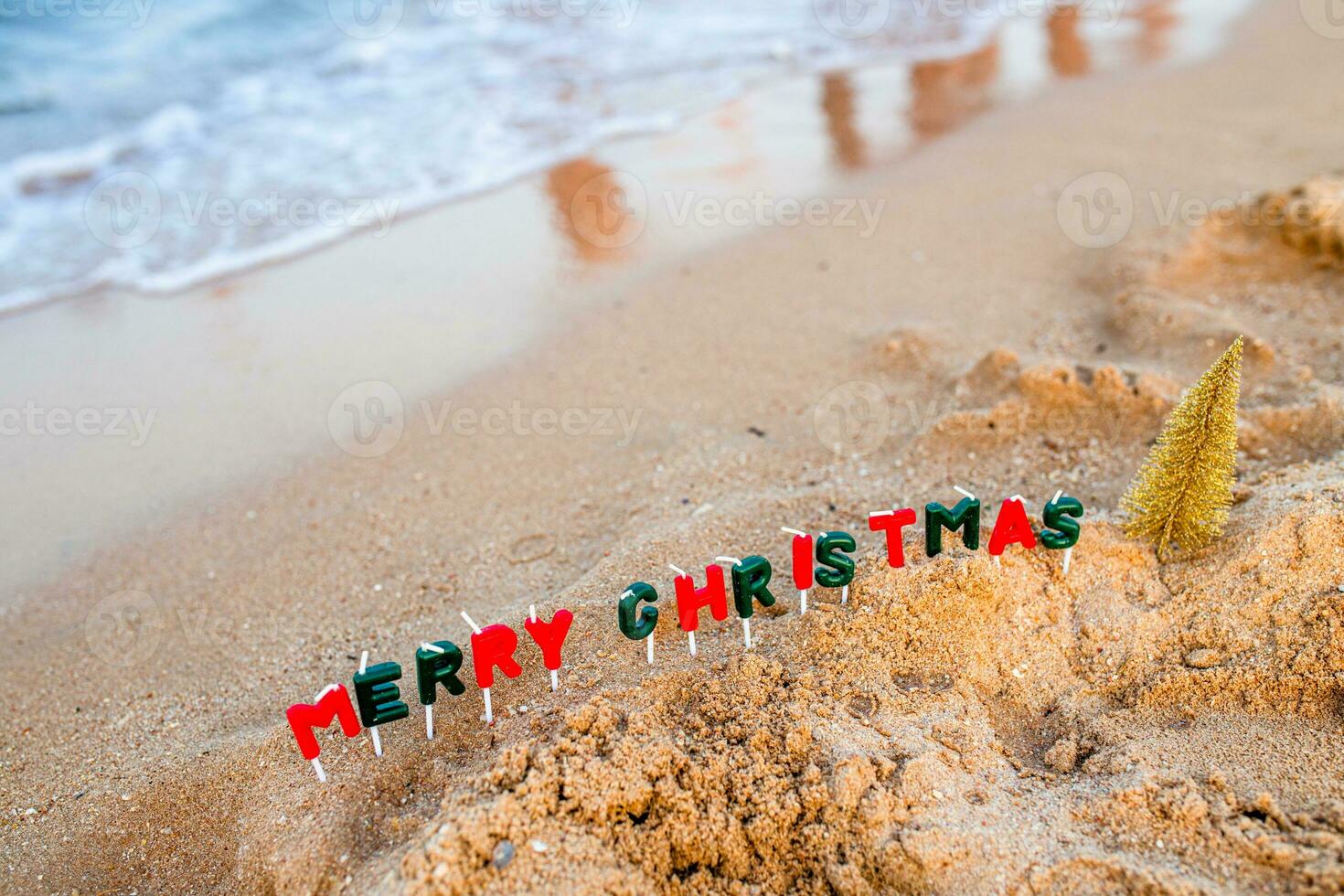 Vacation by the sea. Celebration of the traditional December holiday near the ocean. The text of a Merry Christmas made of candles next to the foaming wave. photo