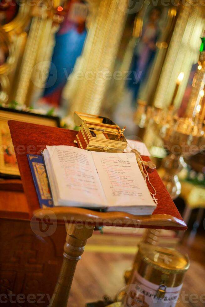 Open bible lying on the altar at the king's gate in the church. The box with things for anointing the child during the christening of the Orthodox church. Soft focus Defocused photo