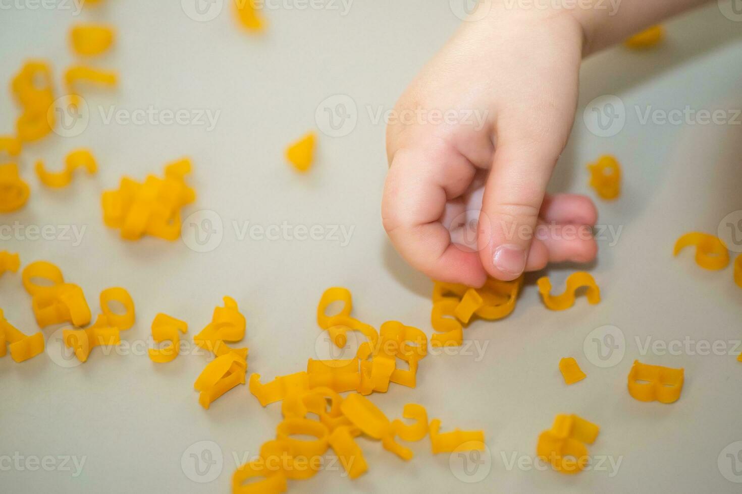 mano de niño coleccionar letras desde pasta desde mesa. desarrollo de multa motor habilidades de manos. montessori técnica. aprender letras y alfabeto en juego foto