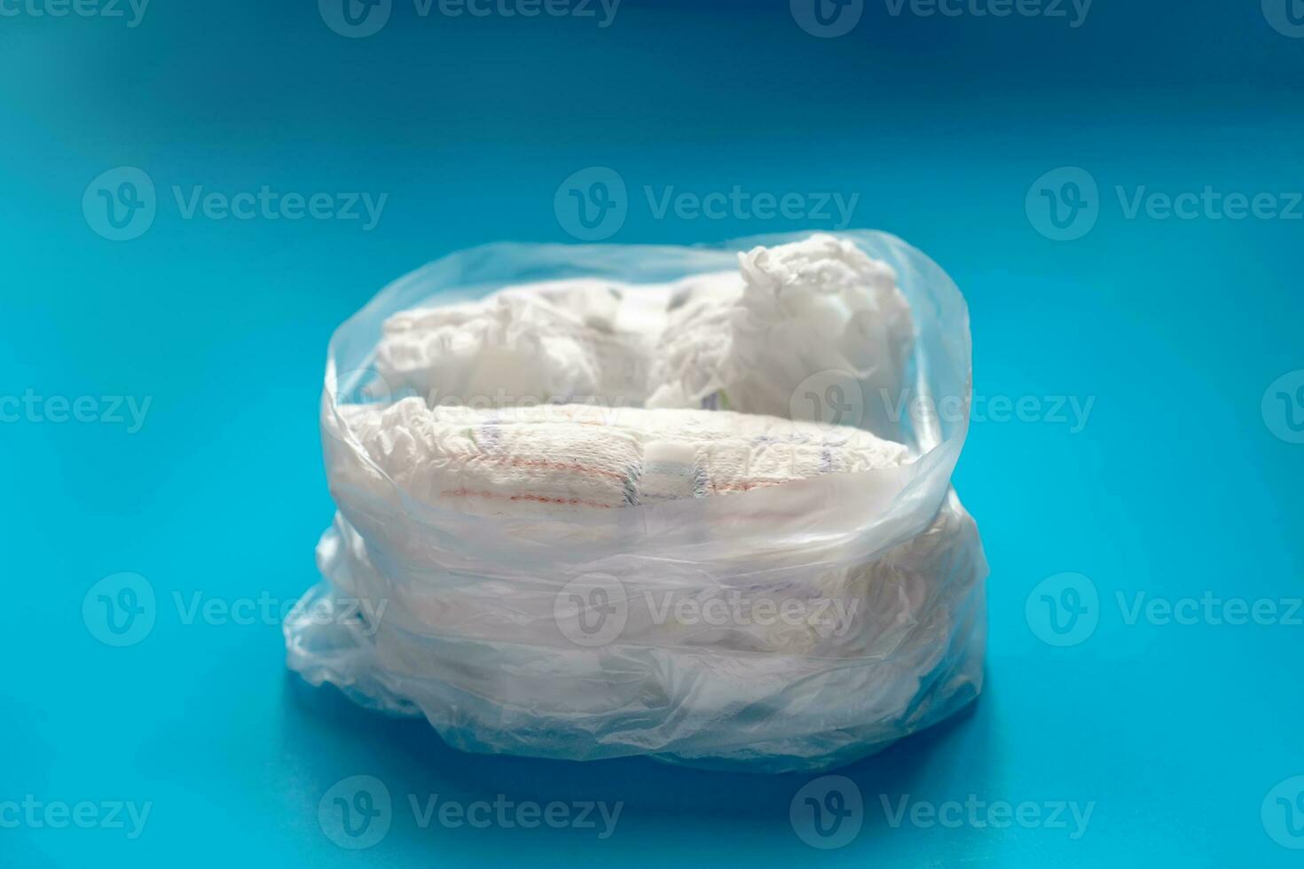 Polyetteline transparent bag with used diapers on blue background. Unprocessed waste. Deficit of diapers during coronavirus quarantine. photo