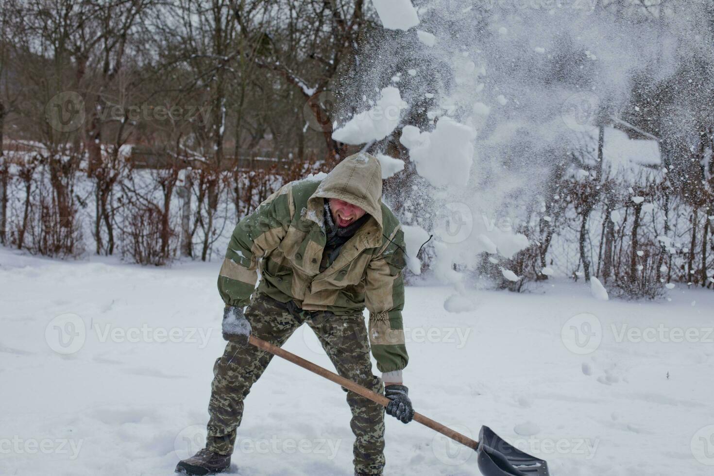 man clears the yard of snow With Shovel. Heavy snowfall in winter. High level of snow. Snowy snowdrift. photo