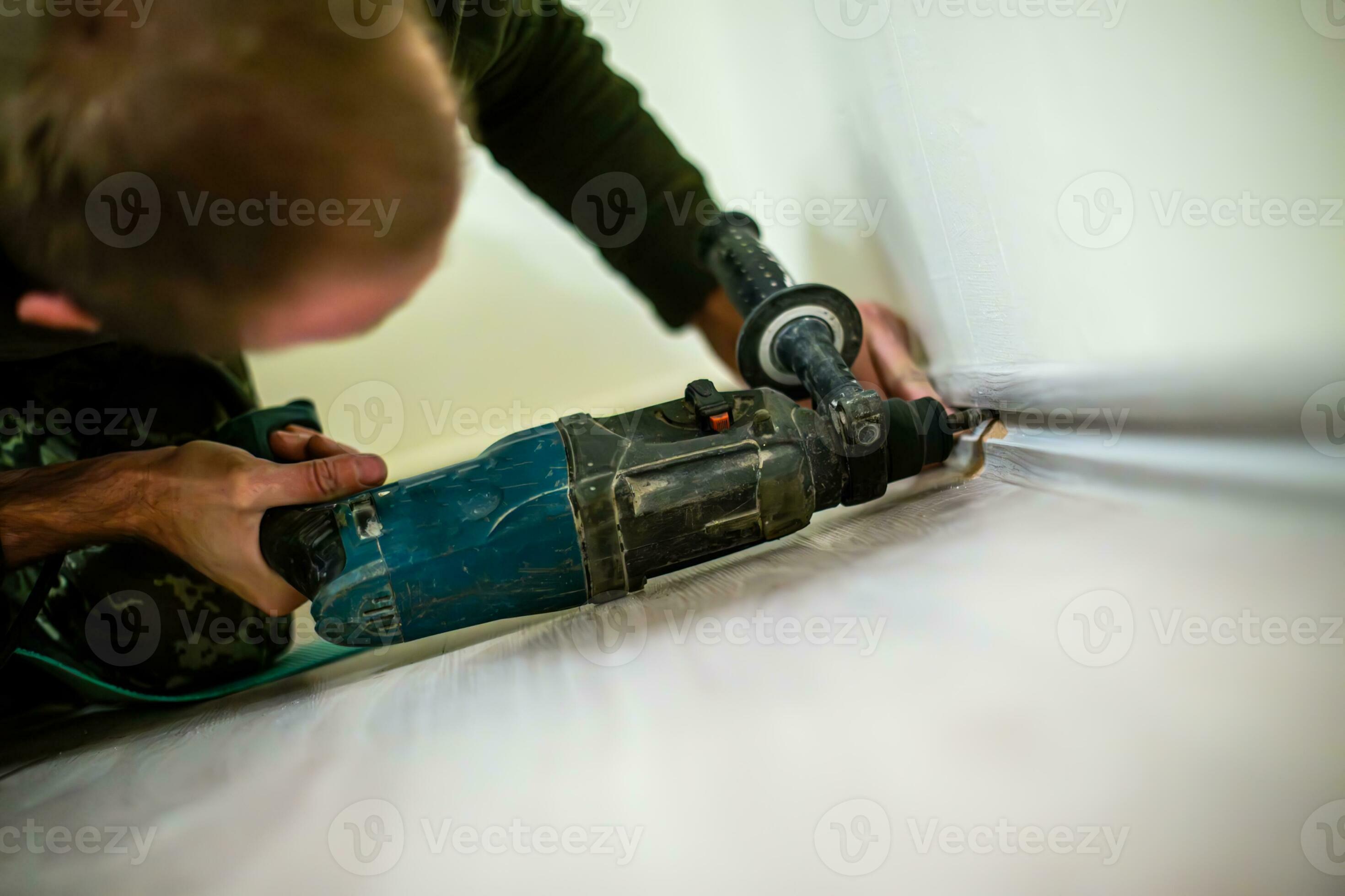 Man drilling a hole in the wall with a drill bit. 34775346 Stock Photo