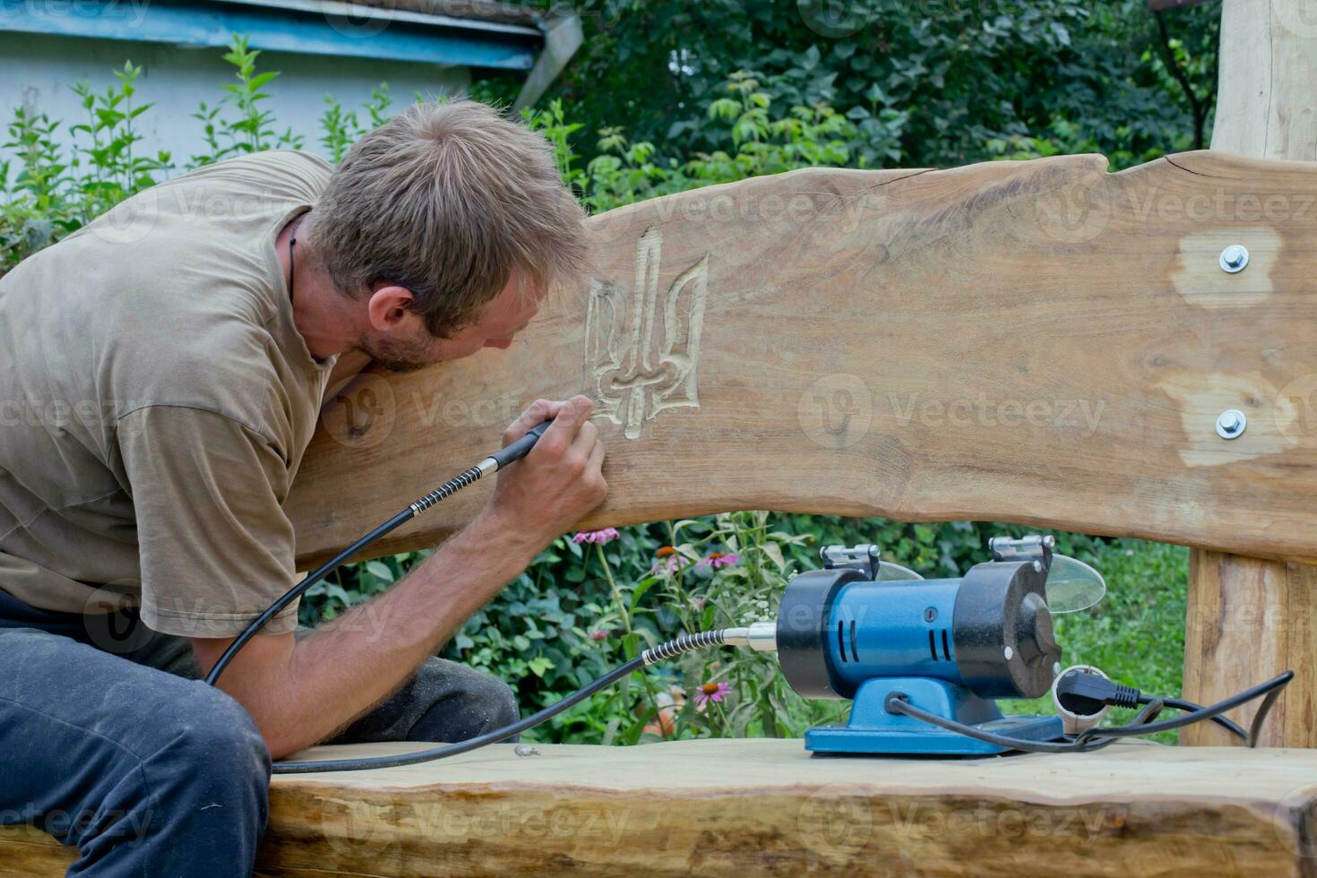 The man carefully cuts out the coat of arms of Ukraine. photo