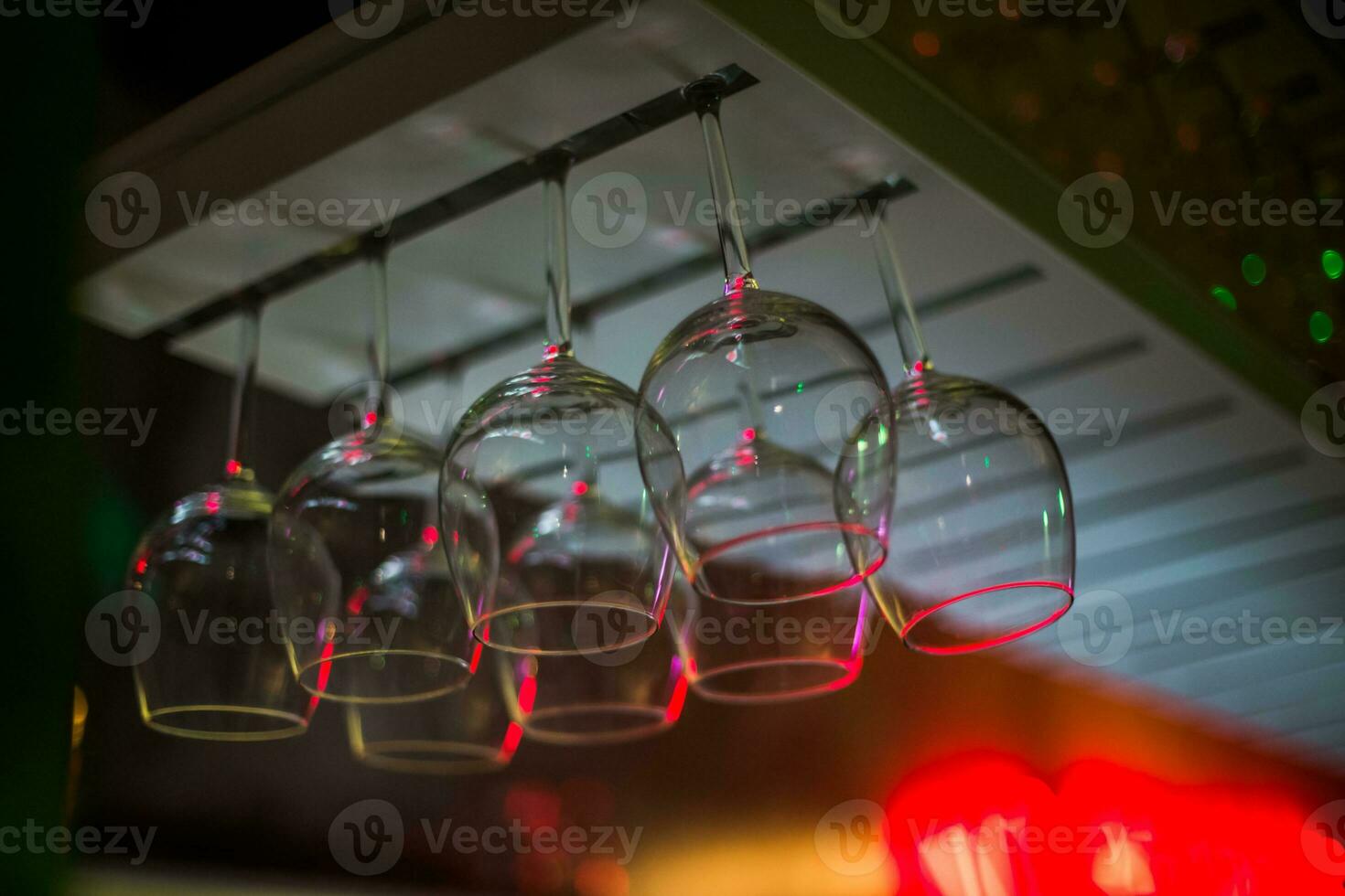 Bocals hanging on the bar. Wine glasses in a restaurant at a party. Light music and laser show in bar or cafe. photo