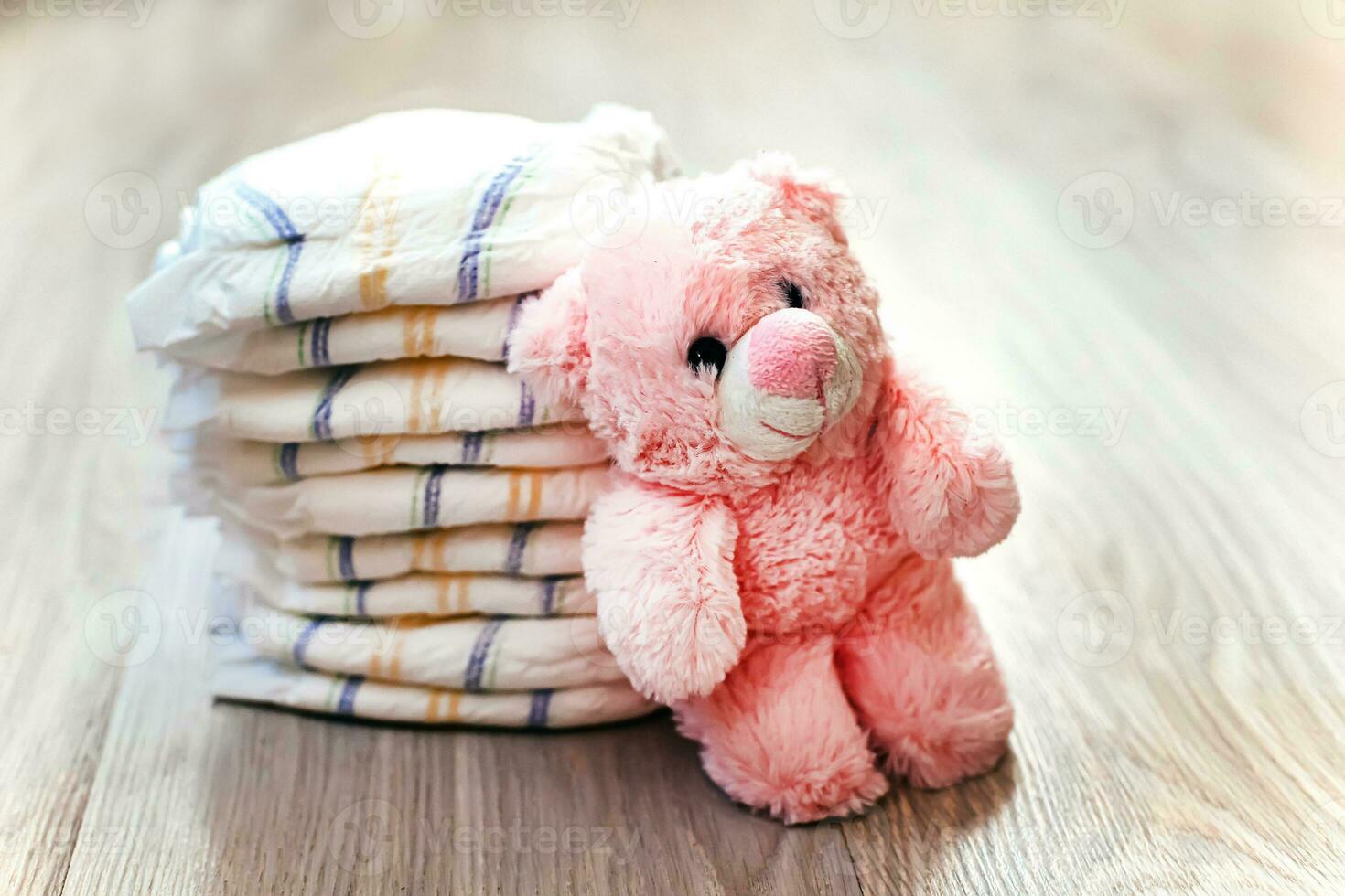 A stack of diapers with a pink teddy bear. Care of the child's body. Remedies for urinary incontinence in newborns. photo