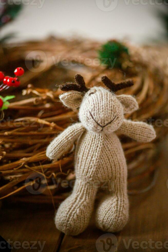Knitted deer near wicker Christmas wreath photo