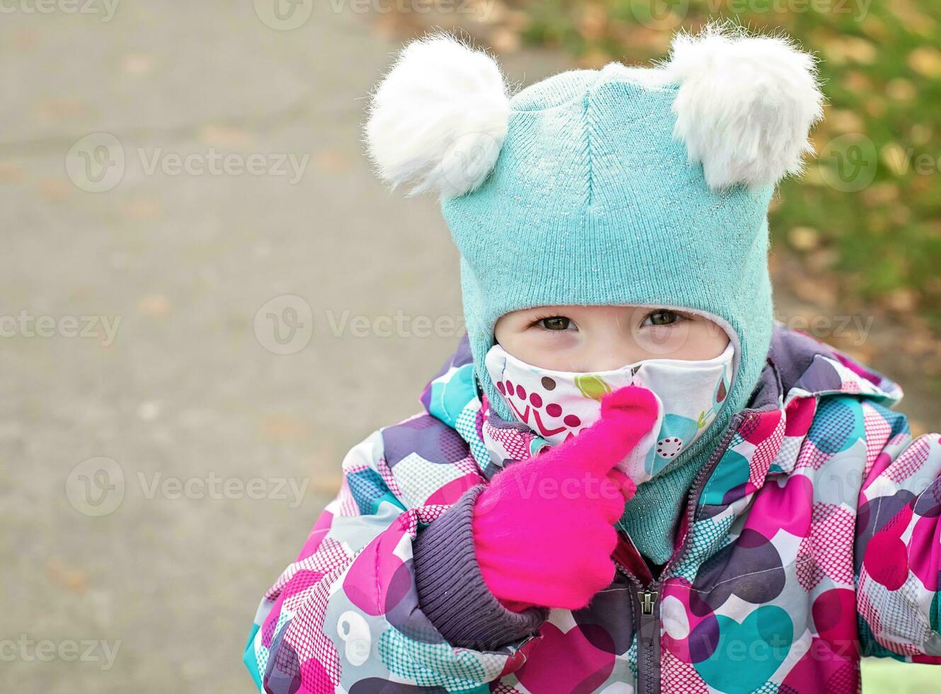 Little girl Pointing finger on face mask and smiling surgical bandage. Coronavirus, illness, infection, quarantine, medical mask, COVID-19. Boy in a medical mask. Quarantine and protection virus, flu, epidemic COVID-19. Coronavirus quarantine. photo