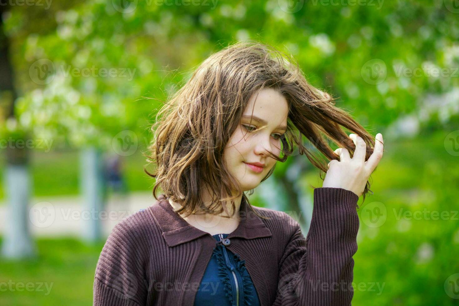 Beautiful girl among cherry flowers in spring. Portrait of a girl with brown hair and green eyes. photo