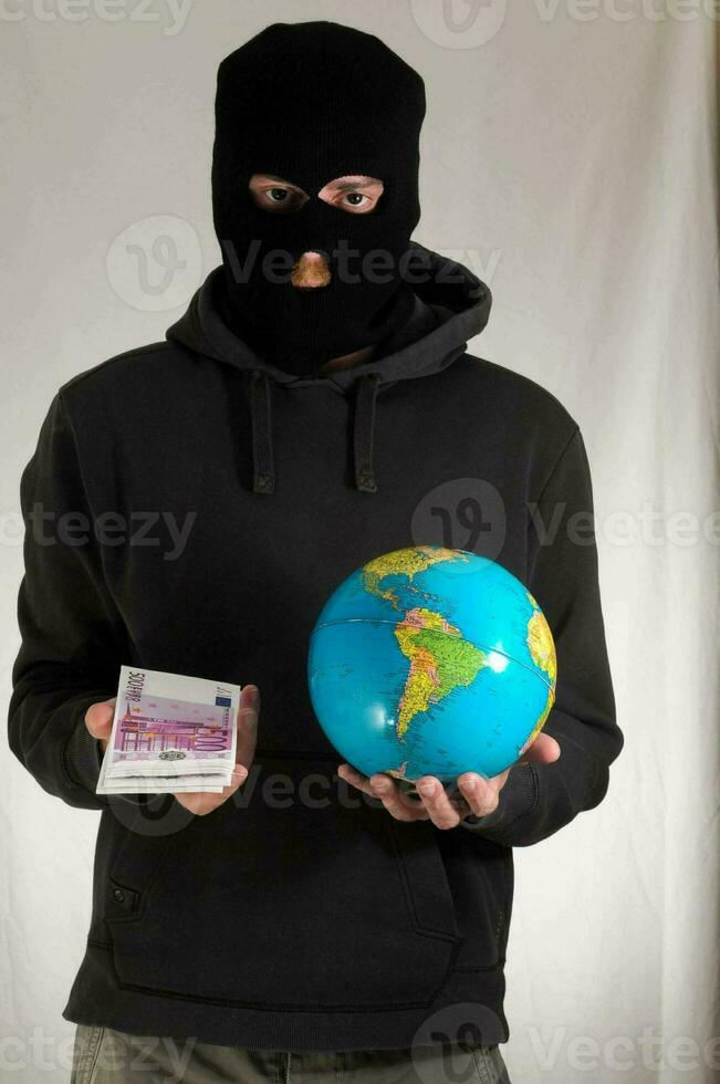 a man in a black hoodie holding a globe and money photo