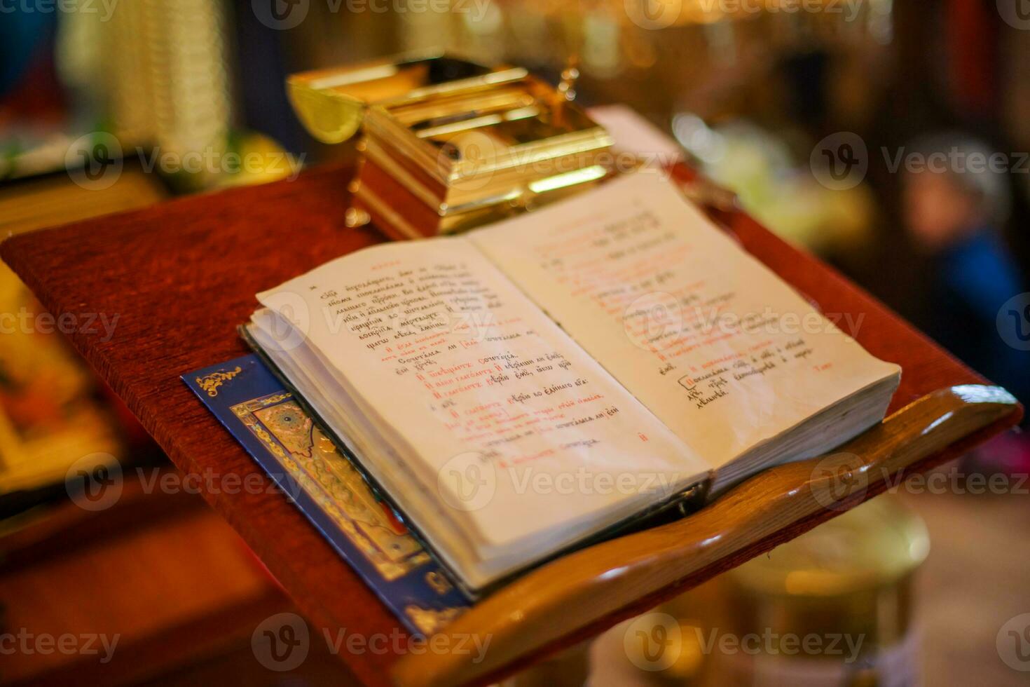 Open bible lying on the altar at the king's gate in the church. The box with things for anointing the child during the christening of the Orthodox church. Soft focus Defocused photo