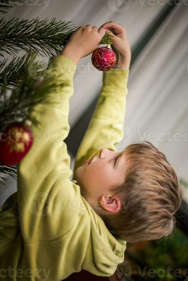 brothers decorate a Christmas tree in a country house before Christmas with simple balls and toys. Family leisure time together on Christmas evening and before the new year 2022 photo