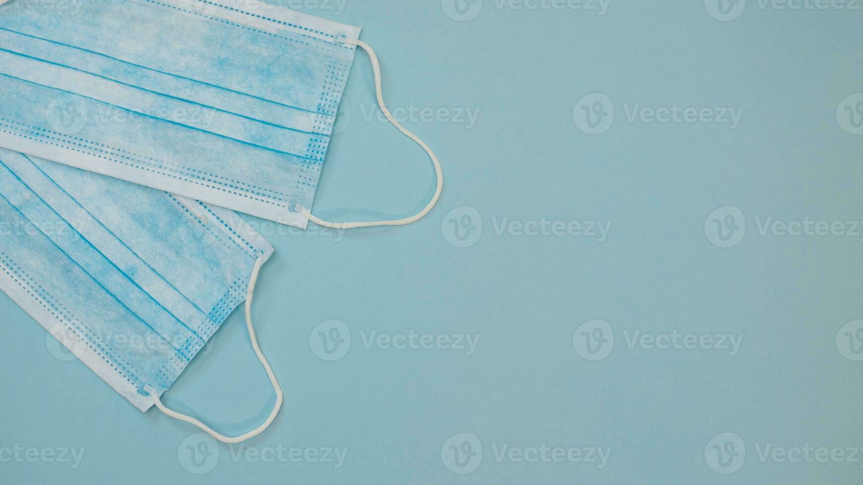 Two Surgical Ear-Loop mask. Protective medical mask on blue background. Framed in square. Coronovirus, quarantine, epidemic, pandemic, cold,illness. Medicine concept and health photo