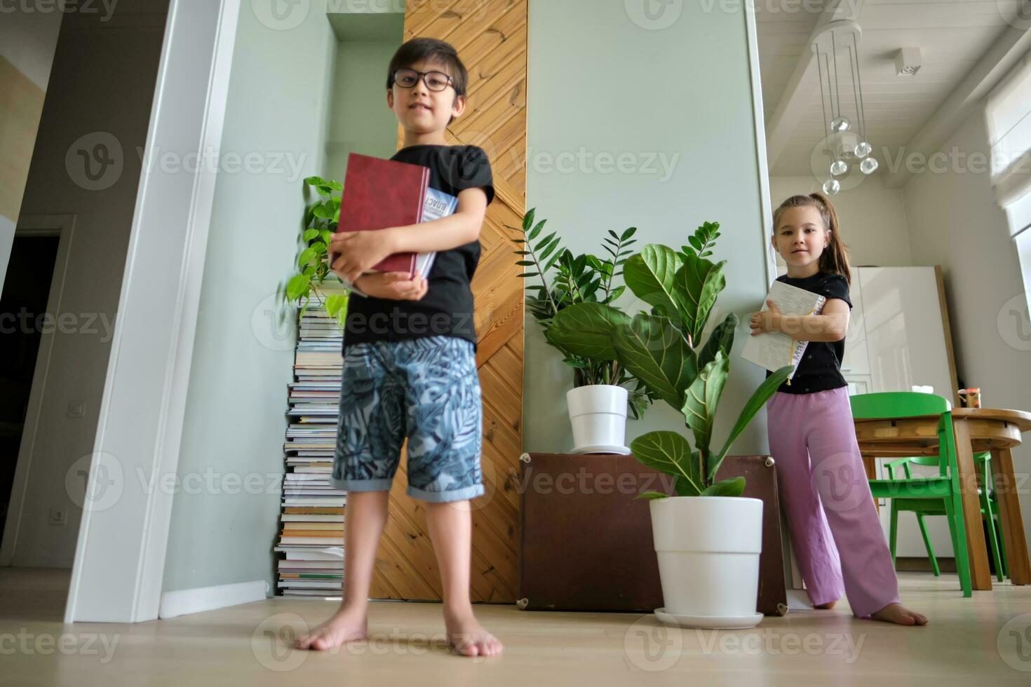 A boy with books in his hands and a girl in the background. photo