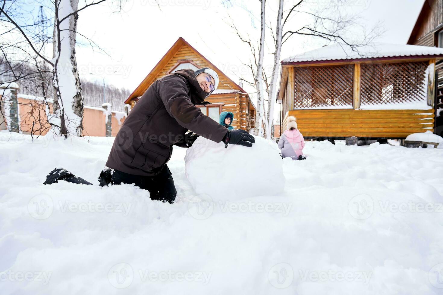 A family builds a snowman out of white snow in the yard in winter. photo