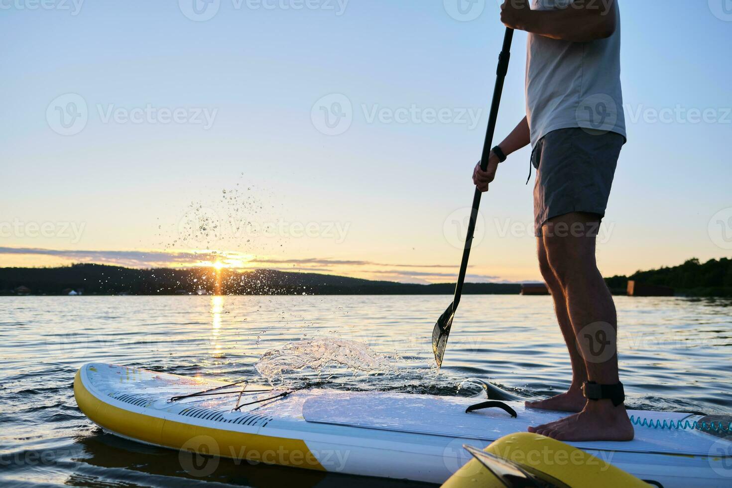 Male legs on a paddle board. photo