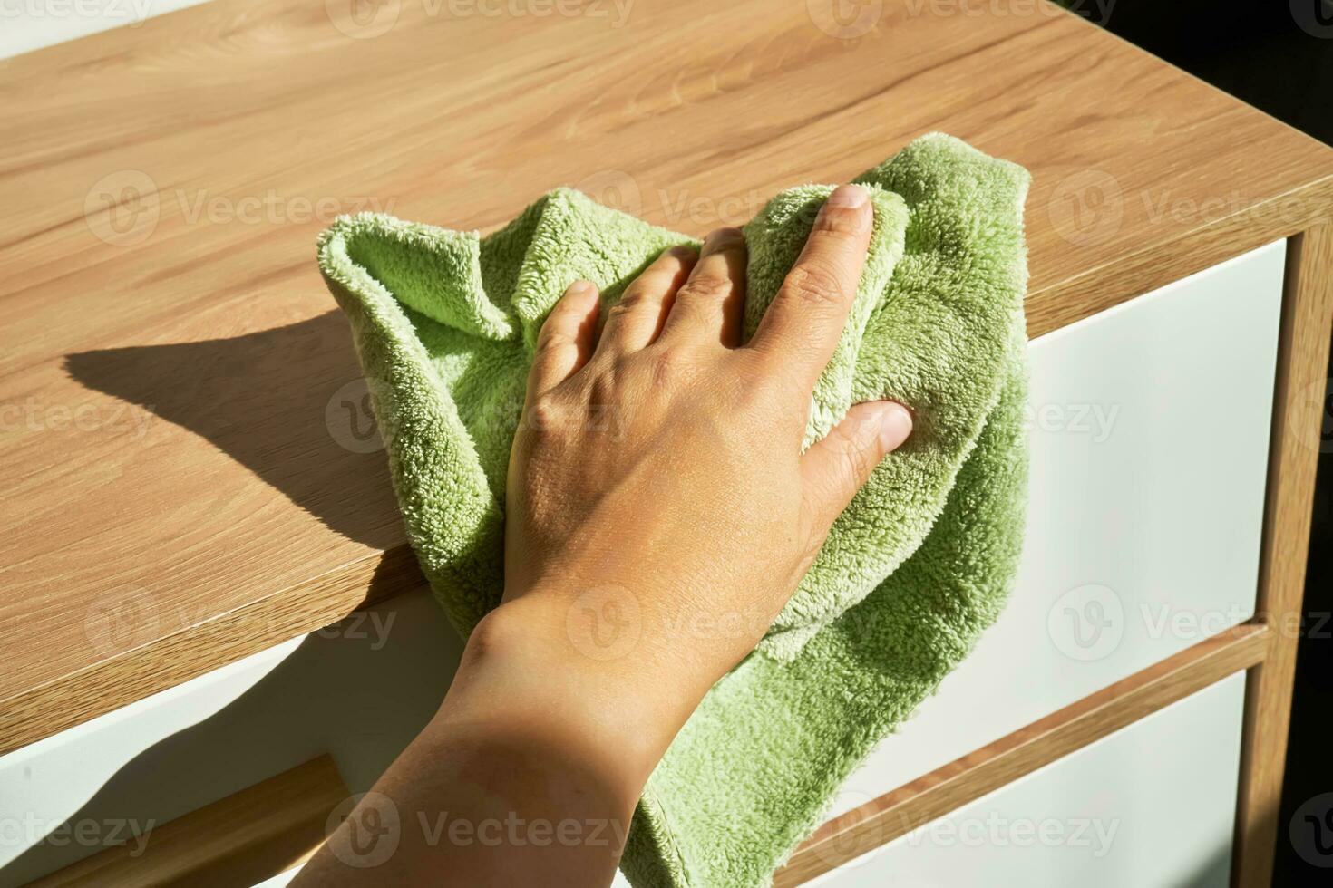 A woman's hand wipes the chest of drawers with a rag. photo