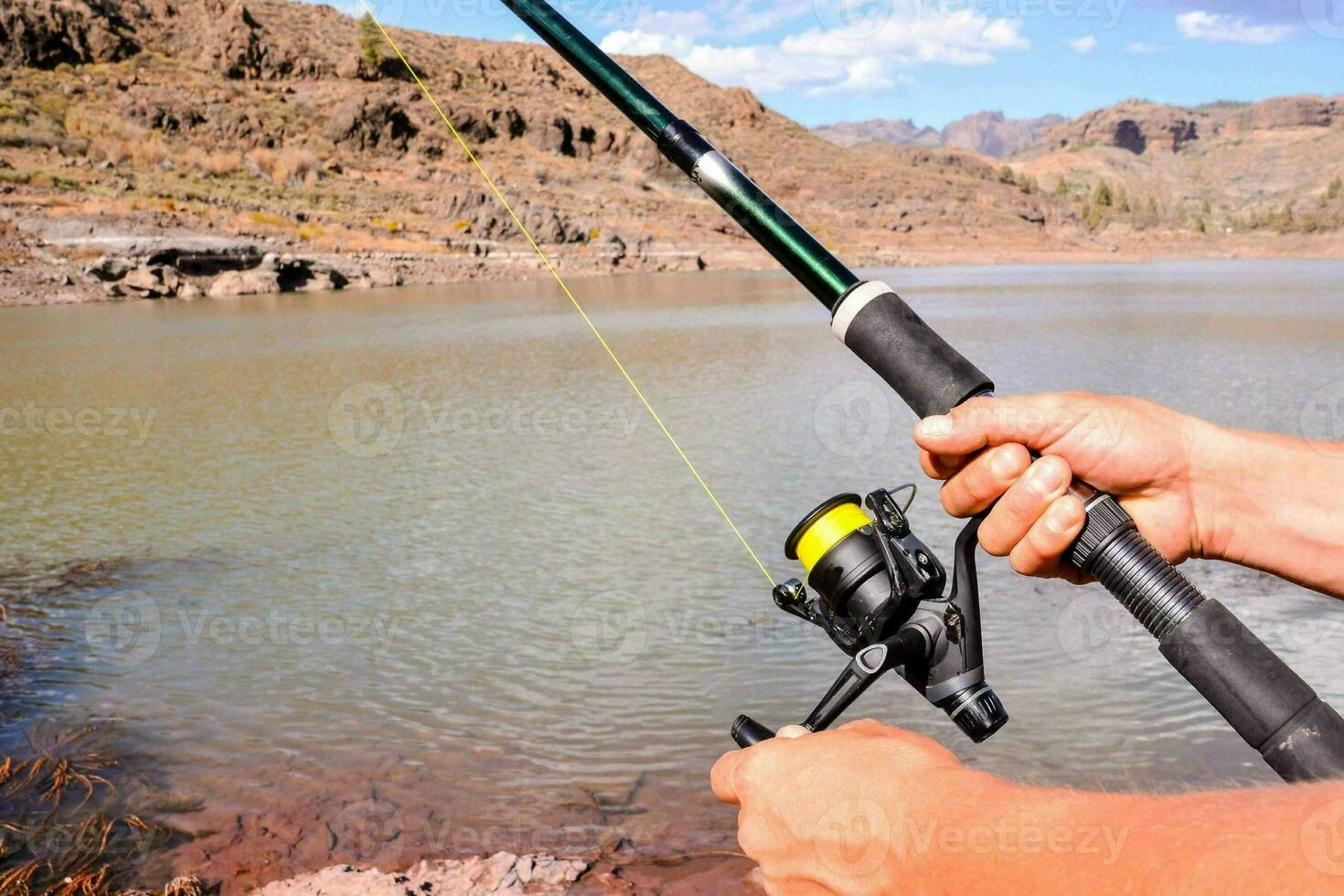 a person holding a fishing rod and reel photo