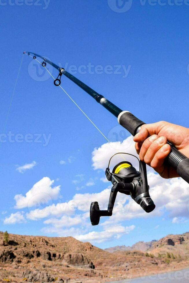 a person holding a fishing rod and reel photo