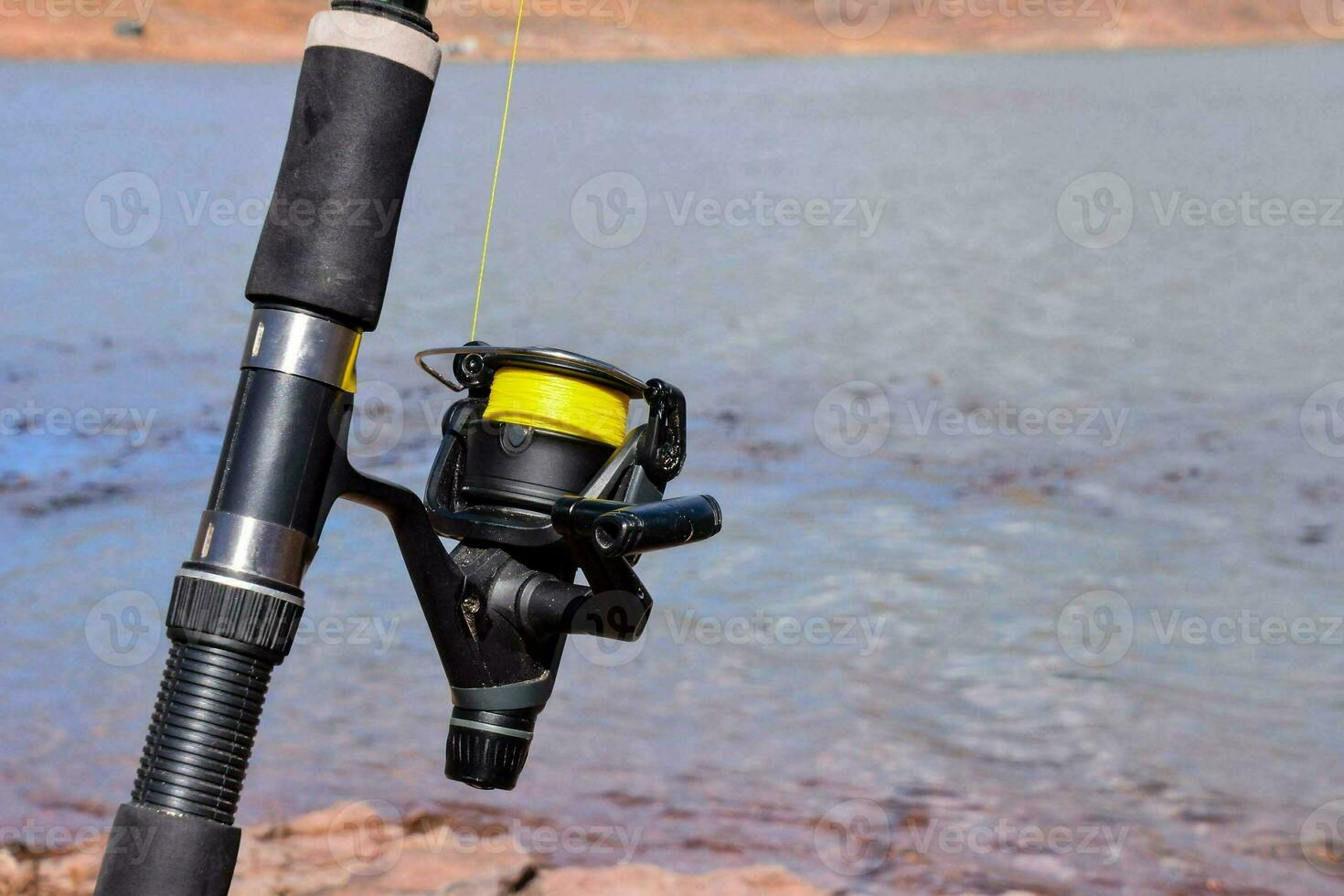 a fishing rod and reel on the shore of a lake photo