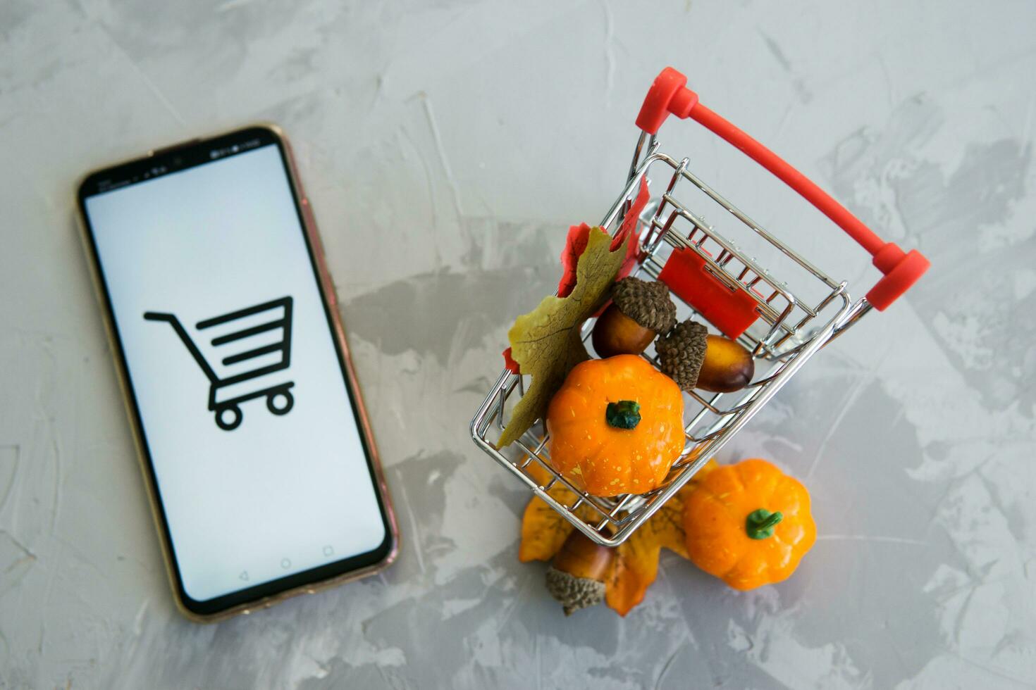 Tver, Russia, September 29, 2020, Smartphone and shopping cart on concrete background. The concept of working in an online store. Sale, discounts and cyber Monday. photo