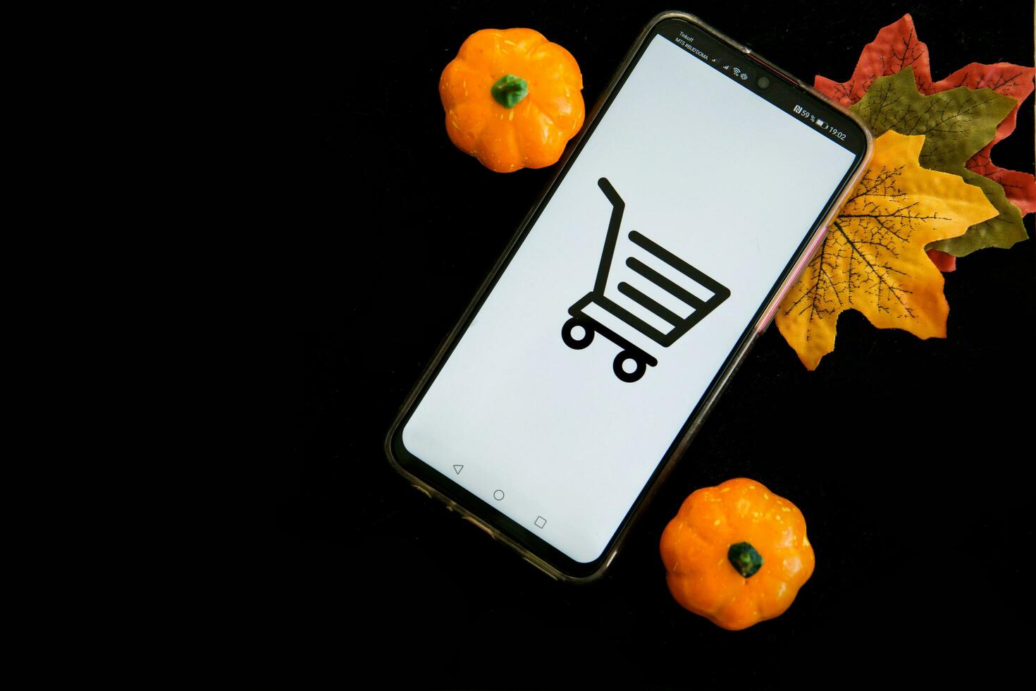 Tver, Russia, September 29, 2020, Smartphone and shopping cart on a black background. The concept of working in an online store. Sale, discounts and cyber Monday. photo