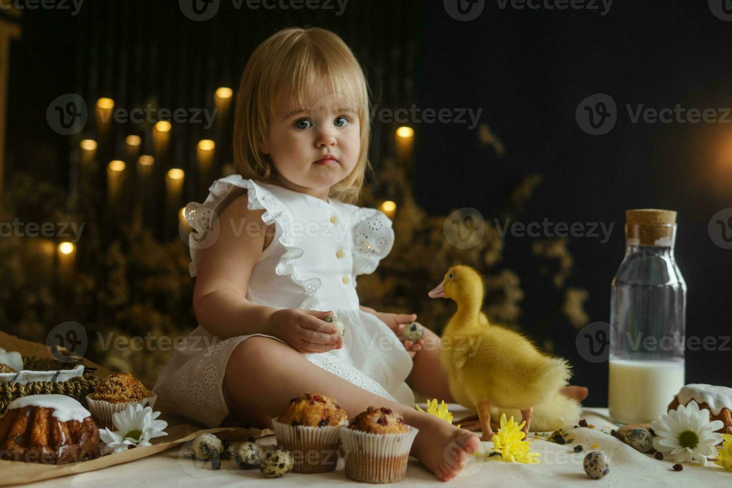 A little girl is sitting on the Easter table and playing with cute fluffy ducklings. The concept of celebrating happy Easter. photo