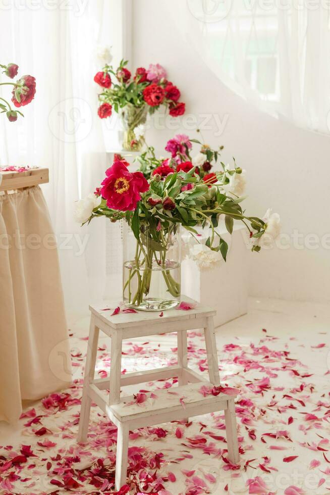 Bouquets with peonies in vases on a white square podium. Decorations with interior flowers. photo