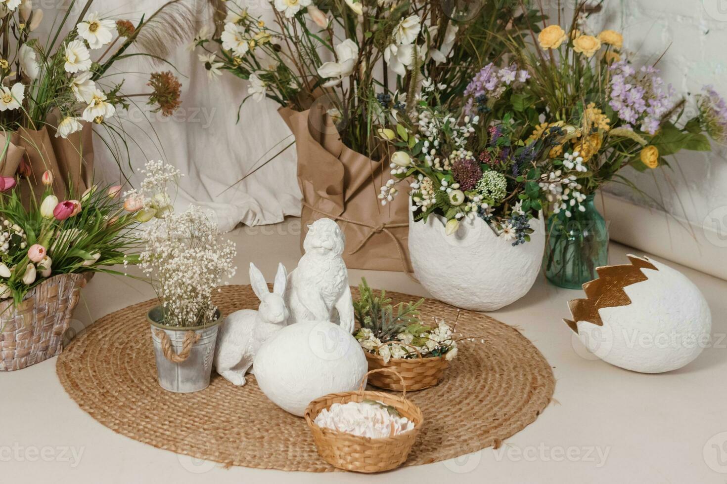 Interior floral Easter composition. Figurines of Easter bunnies and a large eggshell. photo