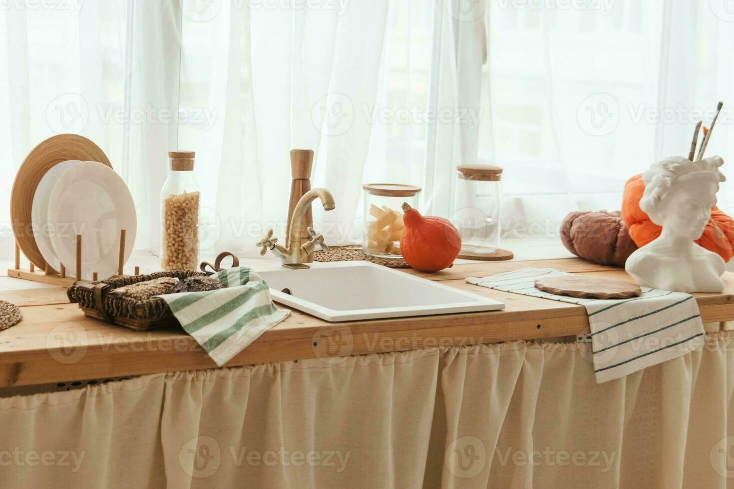 Kitchen countertop by the window in a bright room. Orange pumpkins, bread and pasta on the countertop. Autumn mood at home. photo