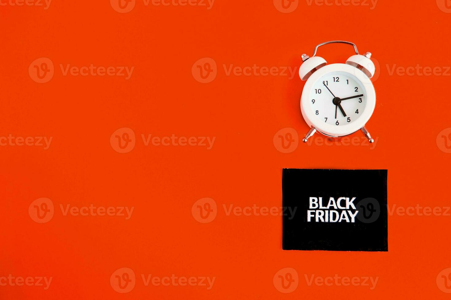white alarm clock and an inscription on a black square - black Friday on a red background. The topic of sales. photo
