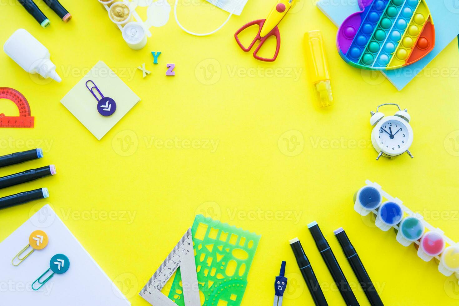 Close up of stationery and silicone toy popit. Flat lay composition. Yellow background. Space for text. Back to school photo