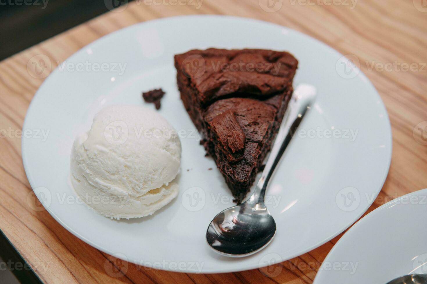 Chocolate brownie with a scoop of ice cream on a white plate. Close up. photo